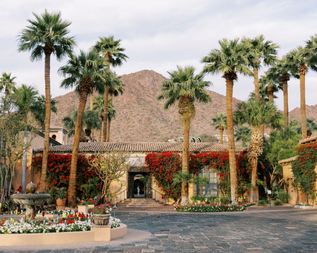 Palm trees, vibrant bougainvillea, and mountain views frame the courtyard entrance of The Royal Palm Resort a Arizona wedding venue.