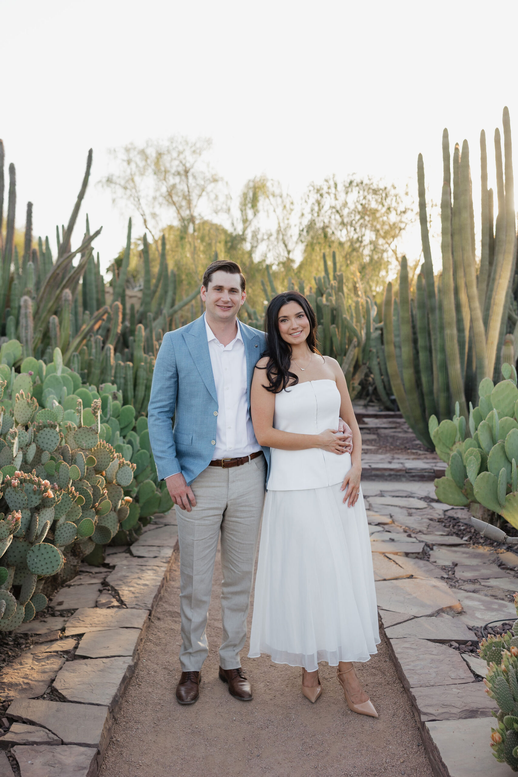 Couple embracing and smiling together surrounded by cacti during an Arizona engagement session